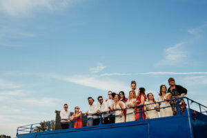 A wedding party on top of a blue, open topped bus