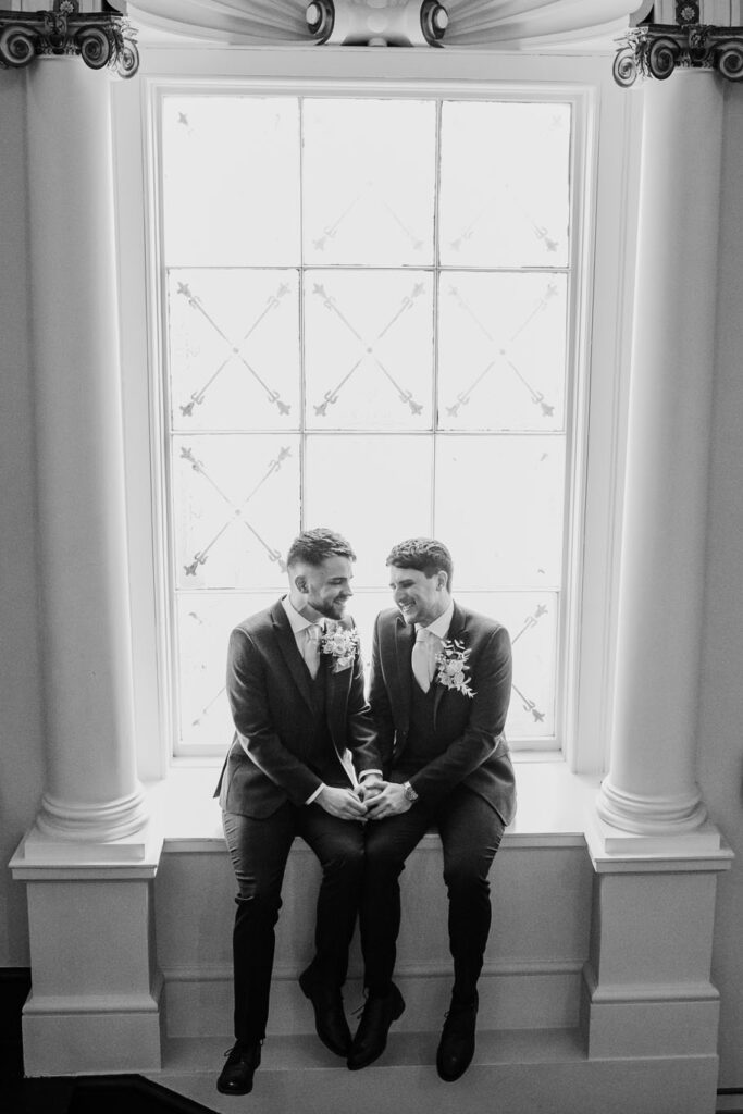 Black & White photo of Groom and Groom sitting in the window holding hands. Hensol Castle Wedding - When Charlie Met Hannah