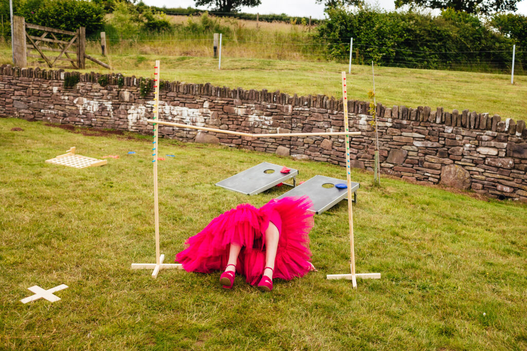 A lady in a pink dress, only visible from the knees down, is lying flat on her back beneath a limbo game