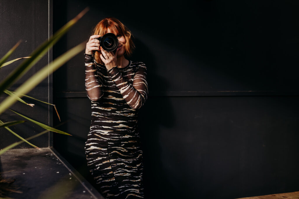 Ginger haired female holding a camera to her face