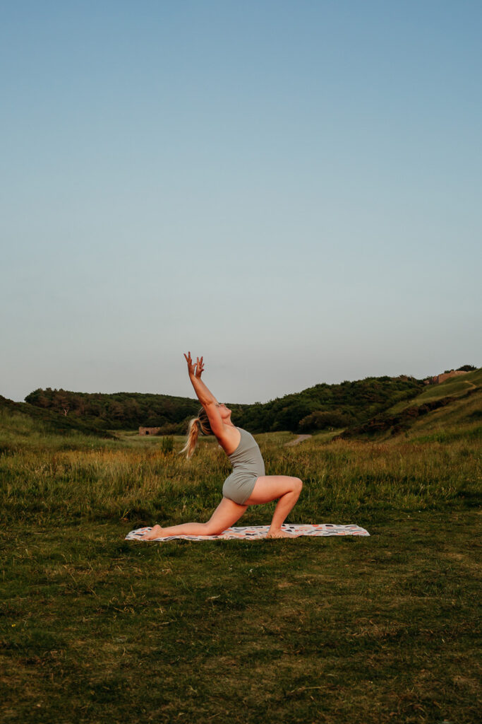 A blonde haired woman doing yoga outdoors in nature