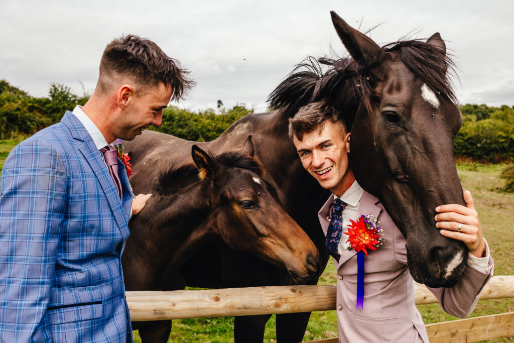 Two grooms, petting and hugging two brown horses (a mum and foal)